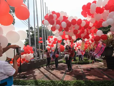 Sejumlah warga berfoto dengan balon berwarna merah putih yang menghiasi halaman Balai Kota, Jakarta, Senin (8/5). Balon-balon tersebut merupakan bentuk dukungan moril untuk Gubernur DKI Jakarta Basuki Tjahaja Purnama (Ahok). (Liputan6.com/Faizal Fanani)