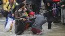 Ribuan migran menyeberangi sungai dengan berpegangan pada seutas tali di perbatasan Yunani-Makedonia, Idomeni, Yunani (14/3/2016). Lebih dari 1.000 migran nekat menembus sungai untuk mencari jalan keluar perbatasan. (Reuters/Stoyan Nenov)