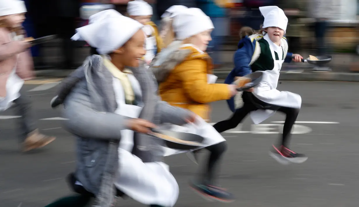 Anak-anak sekolah-sekolah lokal mengambil bagian dalam lomba lari sembari membawa wajan berisi pancake di Olney, Buckinghamshire, Inggris, Selasa (25/2/2020). Peserta kompetisi yang sudah ada sejak tahun 1445 ini harus membolak-balikan pancake sambil tetap berlari. (AP/Alastair Grant)