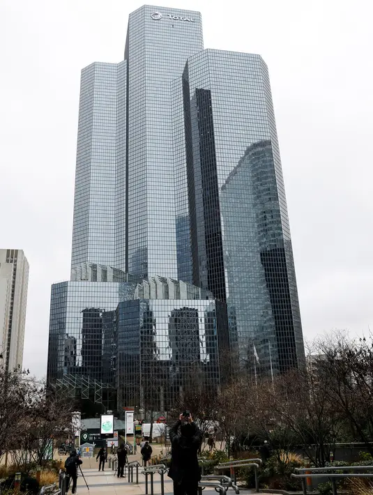 Warga menyaksikan pendaki Alain Robert atau French Spiderman memanjat Menara Total di kawasan bisnis La Defense, Paris, Prancis, Senin (13/1/2020). Alain hanya bermodalkan tangan kosong, sepasang sepatu panjat, dan sekantong kapur bubuk untuk membersihkan keringat. (Thomas SAMSON/AFP)