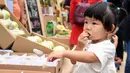 Seorang gadis kecil mencicipi produk-produk pertanian pada acara perayaan untuk menandai festival panen petani China di Distrik Pinggu, Beijing, ibu kota China, pada 24 September 2020. (Xinhua/Ren Chao)