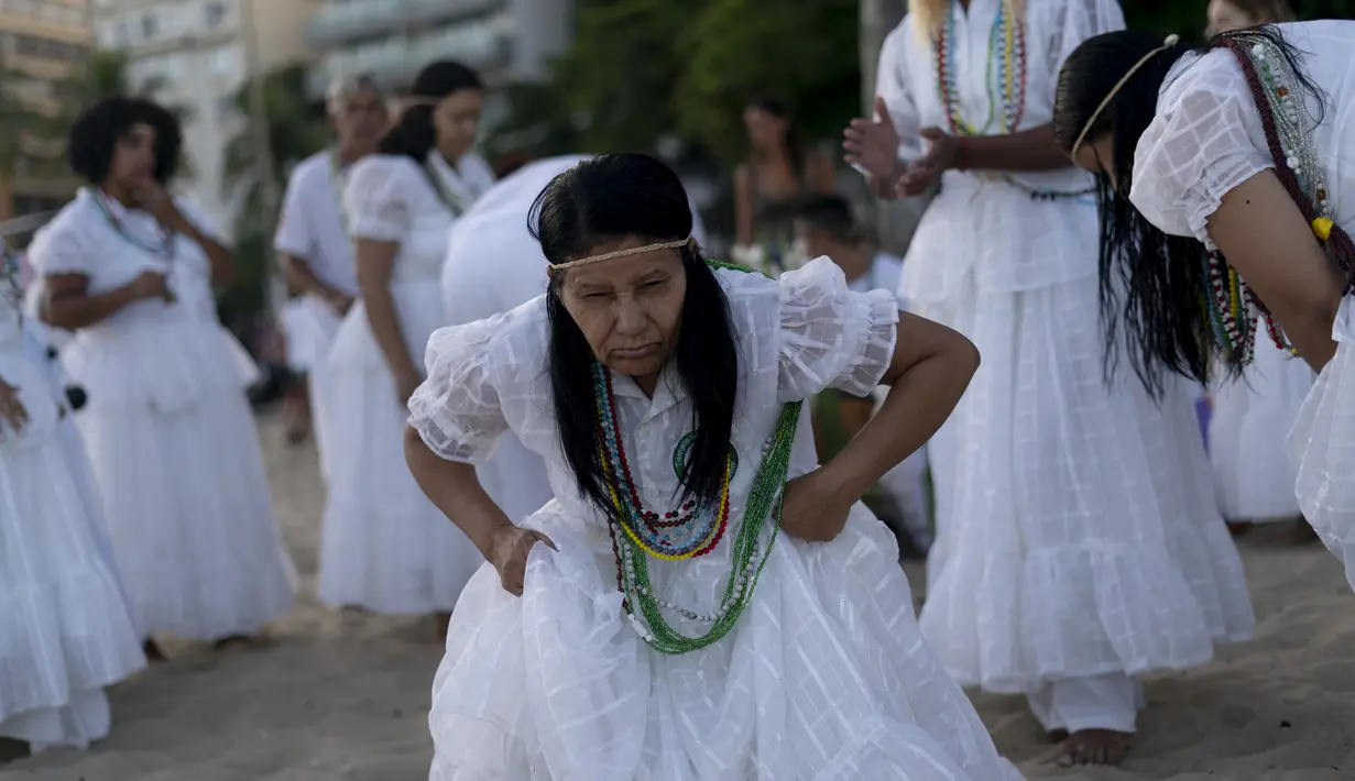 Seorang penganut kepercayaan Afro-Brasil menari saat memberi penghormatan kepada Yemenja sang Dewi Laut, ketika menyambut tahun baru di Pantai Copacabana di Rio de Janeiro (29/12/2019). (AFP/Mauro Pimentel)