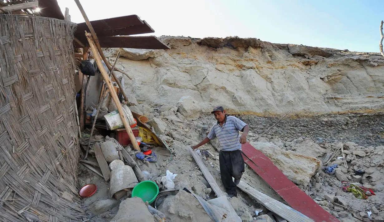 Silverio Apaza berjalan di tengah puing-puing rumahnya yang rusak setelah gempa bumi di Bella Union, Peru, (14/1). Gempa 7,1 skala Richter mengguncang Peru pada Minggu, 14 Januari 2018. (AP Photo / Charlie Reyna)