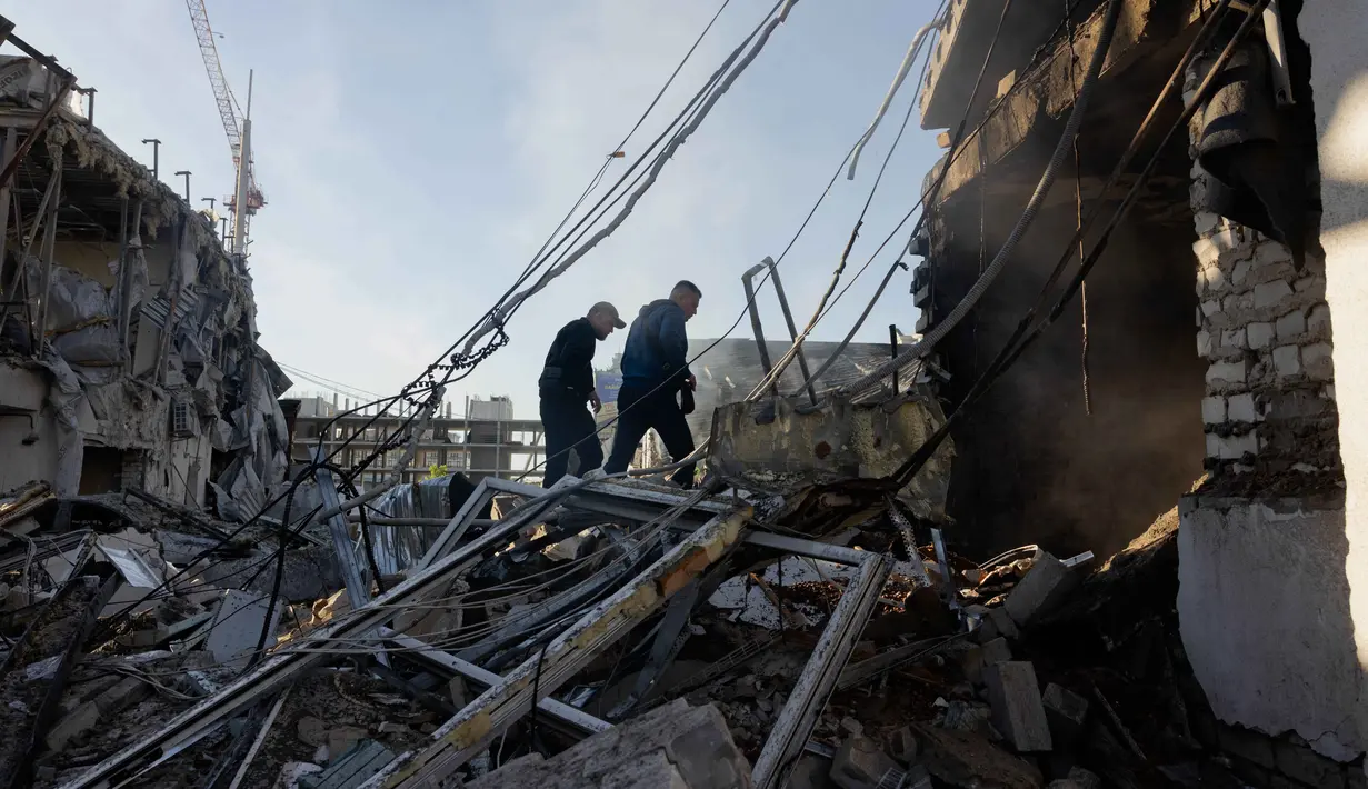 Warga setempat berjalan di dekat dealer mobil yang rusak akibat serangan rudal dan drone besar-besaran Rusia di Kyiv pada Selasa 2 Juni 2026, di tengah invasi Rusia ke Ukraina. (Tetiana DZHAFAROVA/AFP)