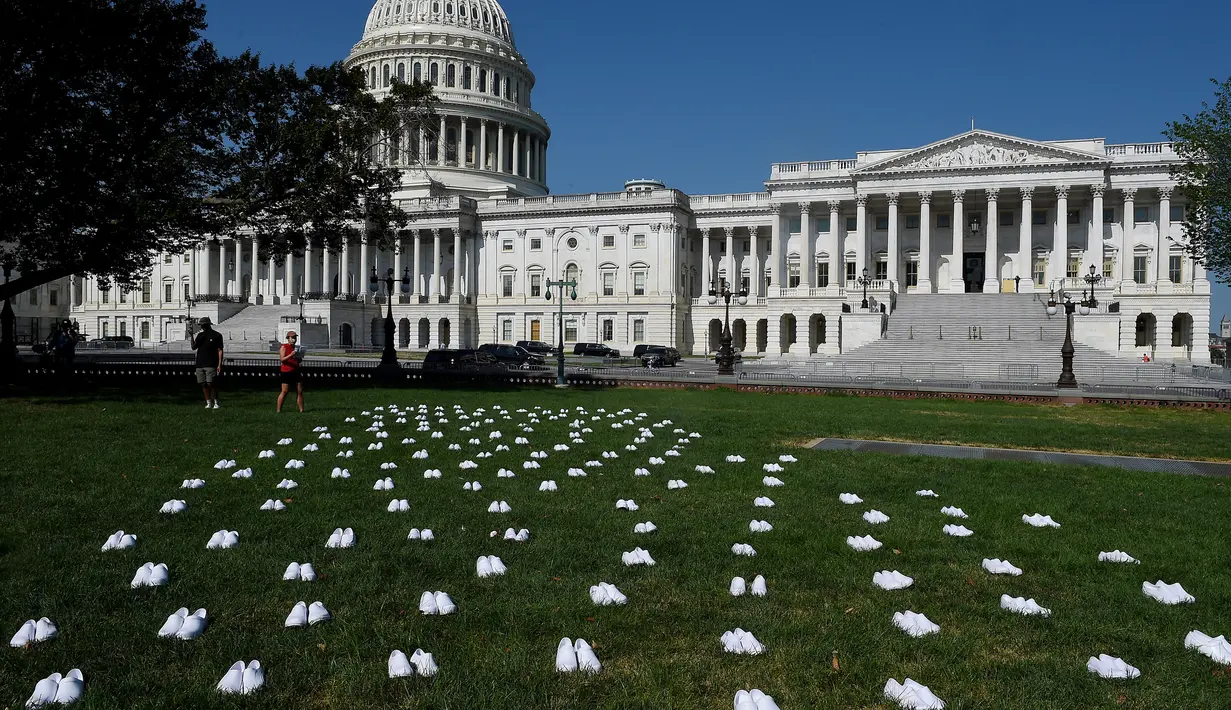 Serikat perawat Amerika Serikat (AS) meletakkan 164 pasang sepatu putih di luar US Capitol di Washington, DC pada Selasa (21/7/2020). Sepatu-sepatu itu melambangkan para perawat yang tewas akibat covid-19 dan menuntut Senat bertindak cepat melindungi perawat di garis depan. (Olivier DOULIERY/AFP)