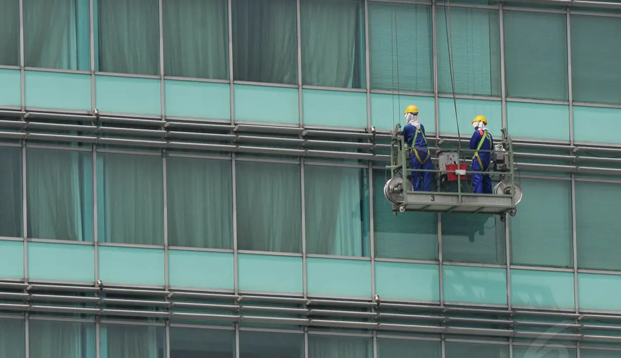 Pekerja terlihat tengah membersihkan kaca gedung di Bundaran HI, Jakarta, dengan menggunakan gondola, Senin (8/9/14). (Liputan6.com/Johan Tallo)