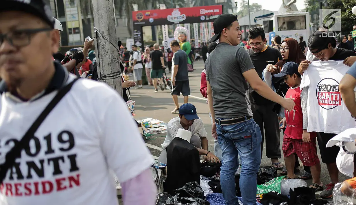 Pembeli memilih kaus #2019GantiPresiden yang dijajakan pedagang saat Car Free Day di Bundaran HI, Jakarta, Minggu (29/4). Memanasnya suasana politik nasional dimanfaatkan pedagang berjualan atribut #2019GantiPresiden. (Liputan6.com/Faizal Fanani)