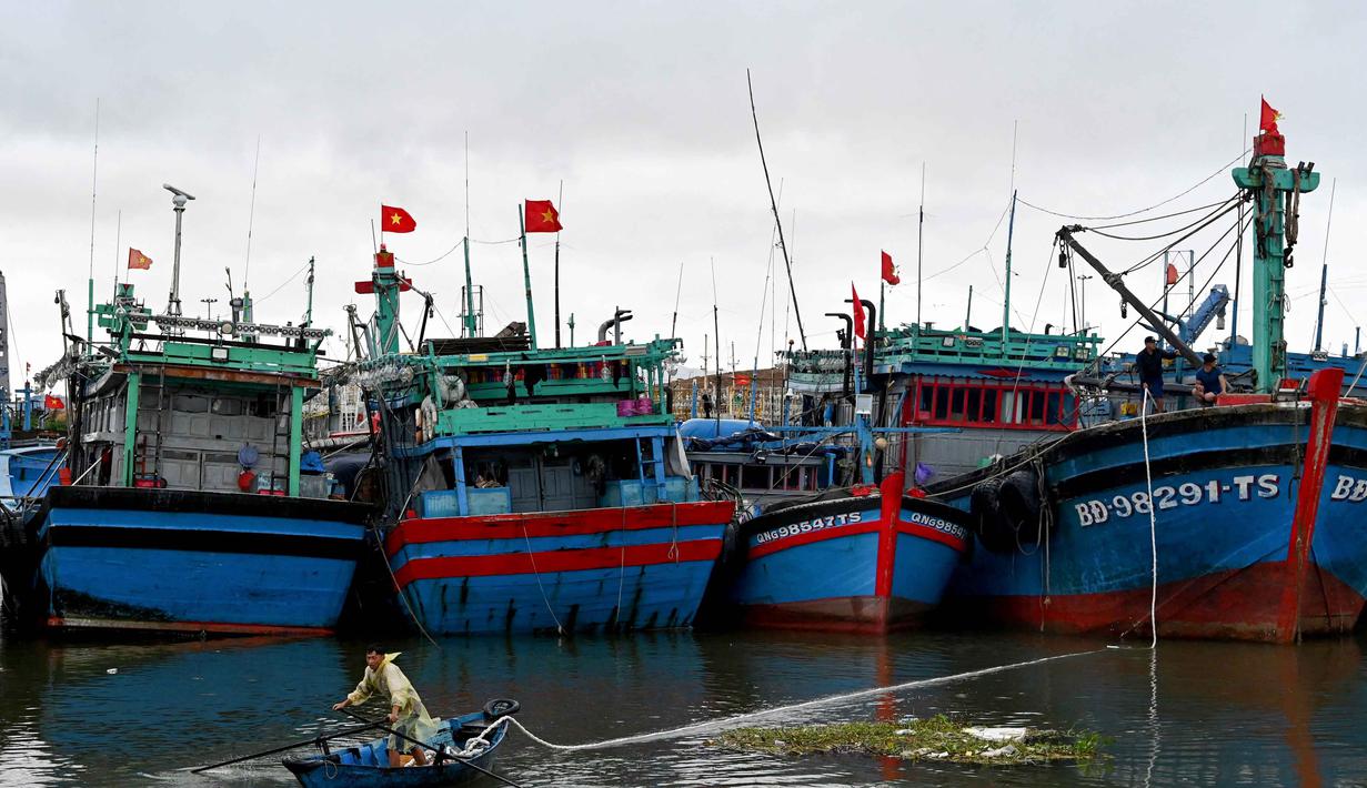 Usai meluluhlantakkan Filipina, Topan Kalmaegi kini mengancam Vietnam. Diperkirakan, Topan Kalmaegi akan menerjang wilayah Vietnam Tengah pada 6 November 2025 malam hari waktu setempat. Tampak dalam foto, seorang pria menarik tali dari perahu nelayan saat orang-orang mempersiapkan perahu untuk menghadapi dampak Topan Kalmaegi di Pelabuhan Nelayan Quy Nhon, Provinsi Gia Lai, Vietnam Tengah, pada 6 November 2025. (Nhac NGUYEN/AFP)