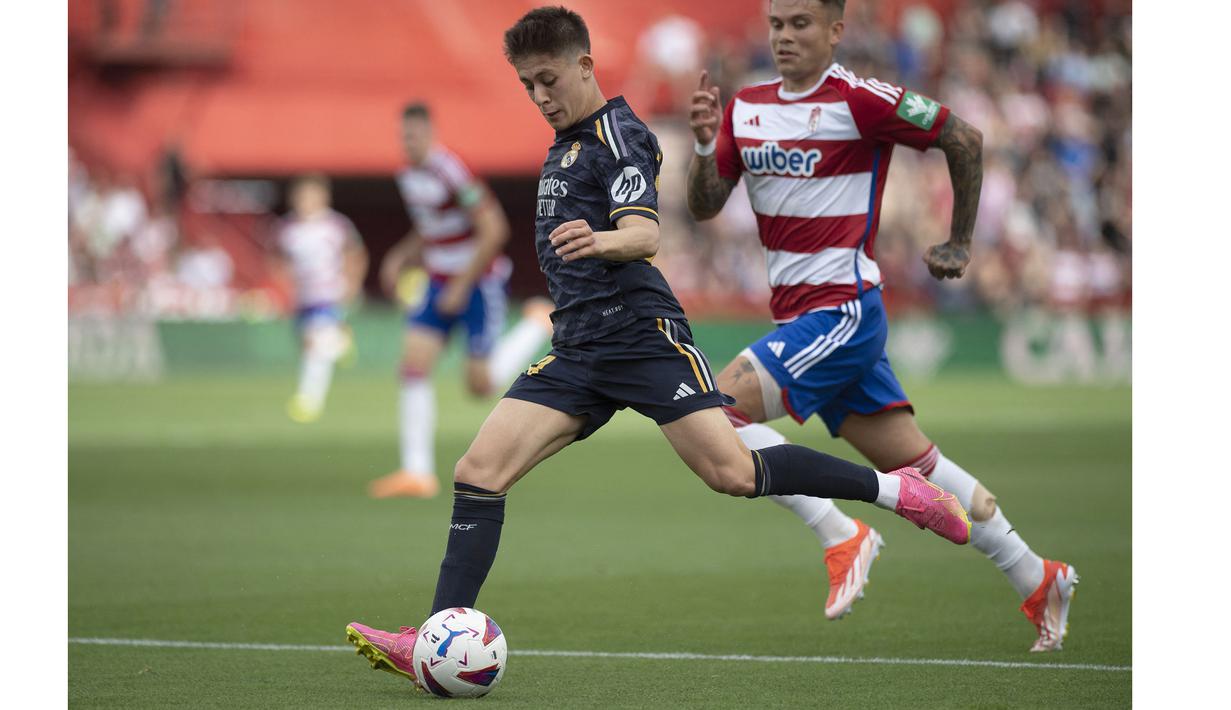 Pemain Real Madrid, Arda Guler (kiri) menggiring bola dibayangi pemain Granda, Kamil Piatkowski pada laga lanjutan Liga Spanyol 2023/2024 di Nuevo Los Carmenes Stadium, Granada, Sabtu (11/05/2024). (AFP/Jorge Guerrero)