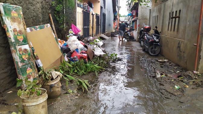 Warga tampak mencuci motor di dekat tumpukan sampah usai banjir merendam wilayah Makasar, Jakarta Timur. (Liputan6.com/Ika Defianti)