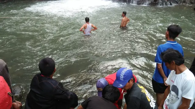 Anggota Basarnas Jawa Barat dibantu warga tengah mengangkat korban tenggelam di area wisata Curug Cikaso, Cisompet, Garut
