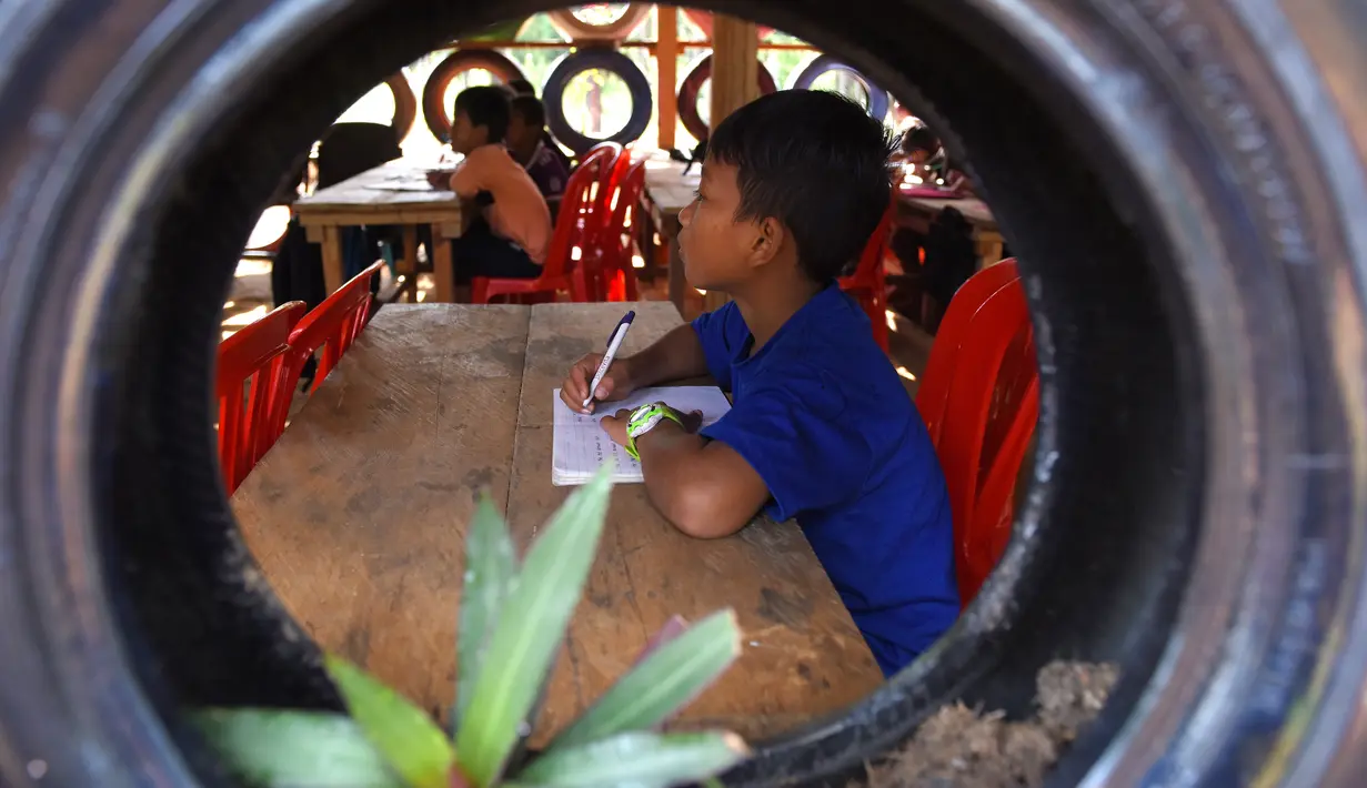 Siswa belajar di ruang kelas berdinding ban mobil yang dicat di Coconut School, Taman Nasional Kirirom Kamboja, 1 Oktober 2018. Sekolah ini didirikan mantan manajer sebuah hotel, Ouk Vanday yang mendambakan Kamboja bebas sampah. (TANG CHHIN Sothy/AFP)