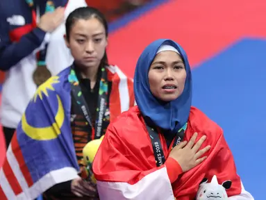 Atlet Taekwondo putri Indonesia, Defia Rosmaniar saat di podium kemenangan Final Women Individual Poomsae di JCC, Jakarta, Minggu (19/8). Defia Rosmaniar meraih emas usai menumbangkan Salahshouri Marjan dari Iran. (Liputan6.com/Helmi Fithriansyah)
