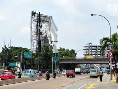 Sejumlah pengendara melintas di dekat papan reklame yang hampir roboh di kawasan Terminal Kampung Melayu, Jakarta (2/10). Hujan deras disertai angin kencang yang mengguyur Ibu Kota kemarin membuat papan reklame ini hampir roboh.(Liputan6.com/Helmi Afandi)