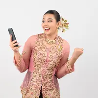 Seorang perempuan mengenakan kebaya sambil memegang HP (Foto Dok: Freepik/johnstocker).