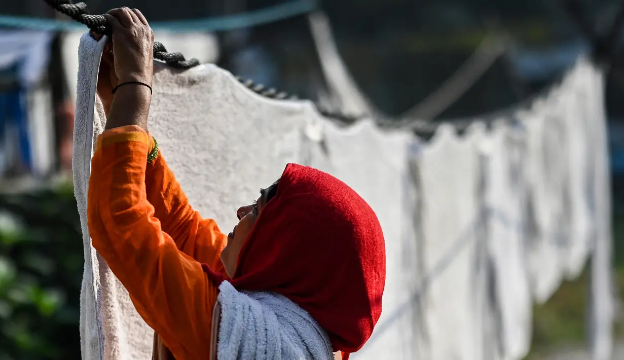 Seorang wanita meletakkan pakaian yang sudah dicuci untuk dikeringkan di binatu terbuka, yang secara lokal disebut 'Dhobi Ghat' di New Delhi, India pada 14 Maret 2022. Dhobi Ghat adalah tempat yang menyediakan layanan cuci dengan cara tradisional. (Money SHARMA / AFP)