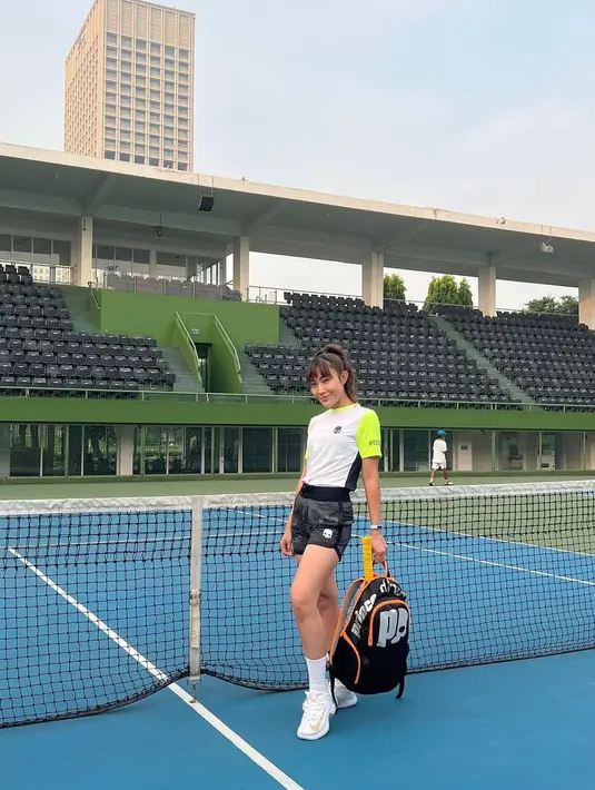 Ayu Dewi juga menjadi salah satu seleb yang menggandrungi olahraga tenis. Dalam foto ini, dirinya terlihat mengenakan outfit tenis lengan pendek dipadu pants hitam, dan sneakers serta kaus kaki tinggi berwarna putih. Foto: Instagram.