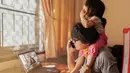 Di sela-sela meeting online dan kesibukan, ayah yang satu ini tetap dengan santai menggendong putrinya tanpa merasa terganggu sedikit pun. (Chatchai.wa/ Shutterstock.com)