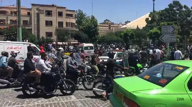 Sejumlah orang berkumpul di depan parlemen Iran di Teheran,  Rabu (7/6). Tiga pria bersenjata dilaporkan melakukan penyerangan di dalam gedung parlemen Iran dengan menggunakan senjata api. (AFP/ATTA KENARE)