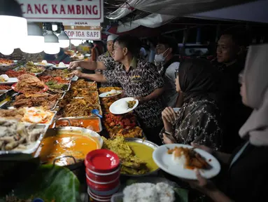 Para pekerja melayani pelanggan dengan hidangan untuk berbuka puasa pada hari kedua bulan suci Ramadan 1447 Hijriah, di sebuah warung makan, Jakarta, Jumat 20 Februari 2026. Setiap Ramadan, terutama ketika masuk waktu berbuka puasa, sentra kuliner Nasi Kapau di Jalan Kramat Raya, Senen, Jakarta Pusat, ramai dikunjungi masyarakat. (AP Photo/Dita Alangkara)