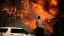 Seorang pria melihat kobaran api yang melahap sebuah rumah akibat kebakaran hutan di Ventura, California, AS (5/12). Dipicu oleh angin kencang Santa Ana, api merambat dengan cepat dan merusak sekitar 26.000 hektare. (AP Photo / Noah Berger)