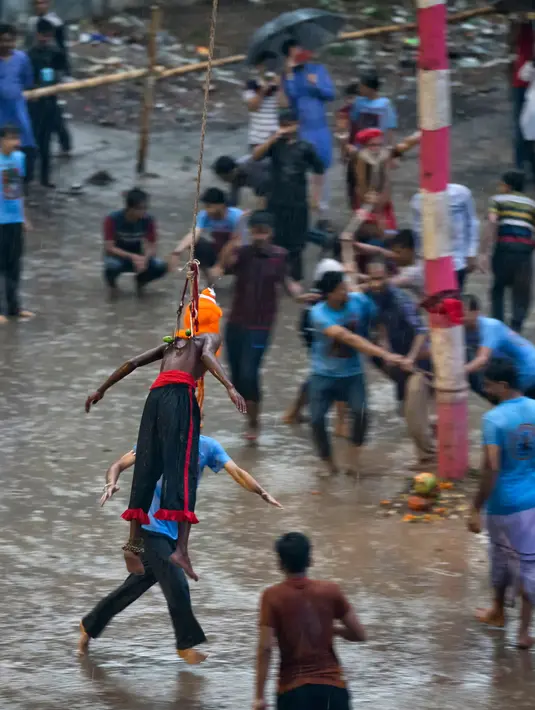 Seorang penganut Hindu tergantung dengan kaitan yang ditusuk di punggungnya saat festival Charak Puja di Dhaka, Bangladesh (14/4). Orang-orang Hindu percaya bahwa festival akan membawa kemakmuran. (AP Photo / A.M. Ahad)