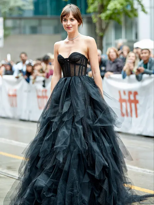 Aktris Dakota Johnson tiba menghadiri pemutaran film "The Friend" di Toronto International Film Festival di Toronto, AS (6/9/2019). Dakota Johnson tampil seksi mengenakan gaun hitam menerawang Dior. (AFP Photo/Geoff Robin)