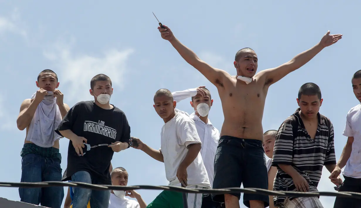 Sekelompok narapidana remaja berdiri diatap saat kerushuan di penjara Juvenile Gaviotas di Guatemala City, Guatemala (3/7). Akibat kerusuhan tersebut, 10 narapidana remaja dilaporkan melarikan diri dari penjara. (AP Photo / Moises Castillo)