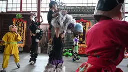 Dengan mengenakan celana panjang berpayet berbulu dan atasan hitam, Lin Xinmeng menjadi bagian dari pemain dalam tarian barongsai. (Jade GAO/AFP)