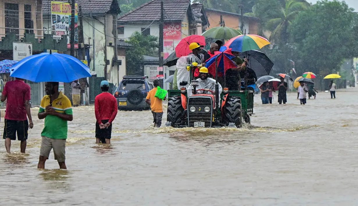 Sedikitnya 56 orang tewas dan 23 lainnya hilang dalam banjir besar selama sepuluh hari dan tanah longsor di Sri Lanka. Tampak dalam foto, warga berjalan di jalan yang terendam banjir setelah hujan deras di Kaduwela, pinggiran Kolombo, pada Jumat 28 November 2025. (Ishara S. KODIKARA/AFP)