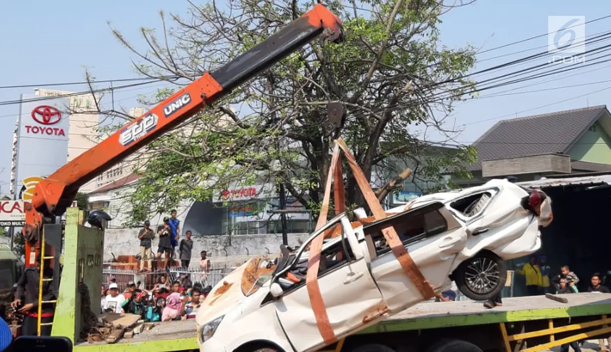 Petugas derek mengevakuasi bangkai mobil kecelakaan maut yang hancur tertindih badan truk muatan tanah di Karawaci, Tangerang, Kamis (1/8/2019). Lima orang penumpang minibus menjadi korban, empat diantaranya meninggal dan satu balita berhasil diselamatkan warga. (Liputan6.com/Pramita Tristiawati)