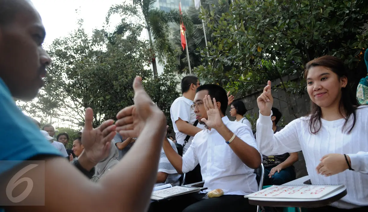 Pelatih mengajarkan bahasa isyarat saat aksi sosialisasi di Car Free Day (CFD), Jakarta, Minggu (11/9). Sosialisasi belajar bahasa isyarat untuk mengkampanyekan penggunaan bahasa isyarat dalam dialog para penyandang tuna rungu (Liputan6.com/Faizal Fanani)