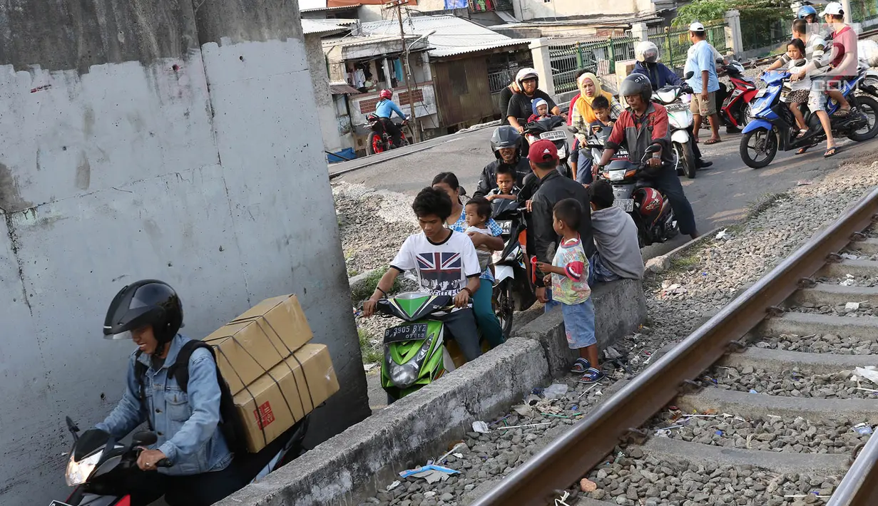 Pengendara sepeda motor melintasi jalan setapak di pinggir rel kereta di kawasan Tambora, Jakarta, Senin (10/7). Tidak tersedianya akses jalan untuk putar balik membuat warga terpaksa memanfaatkan jalan setapak tersebut. (Liputan6.com/Immanuel Antonius)