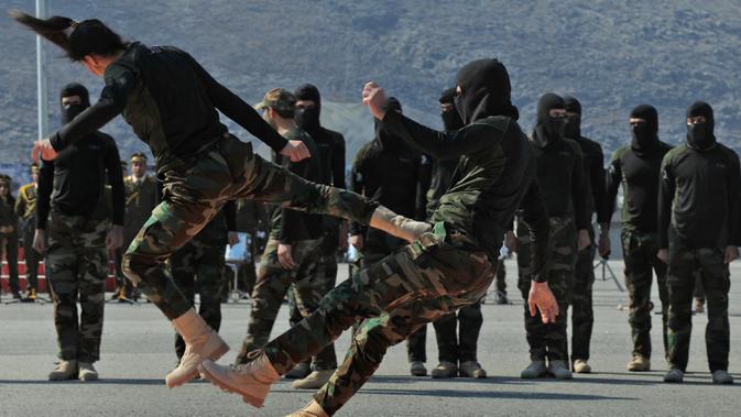 Pasukan perempuan Peshmerga bertarung melawan pria saat berlatihan dalam upacara kelulusan di Kota Soran, Irak, Rabu (12/2/2020). Latihan militer pasukan bersenjata Kurdi tersebut dilakukan sekitar 100 kilometer timur laut ibu kota otonomi wilayah Kurdi di Irak, Arbil. (SAFIN HAMED/AFP)