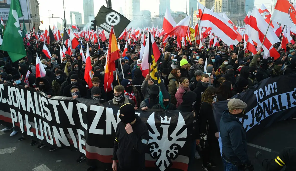 Orang-orang mengibarkan bendera nasional Polandia saat pawai untuk menandai Hari Kemerdekaan Nasional Polandia di Warsawa, Polandia, 11 November 2021. Hari Kemerdekaan Nasional Polandia dirayakan pada 11 November untuk memperingati ulang tahun Republik Polandia Kedua. (Adam Chelstowski/AFP)