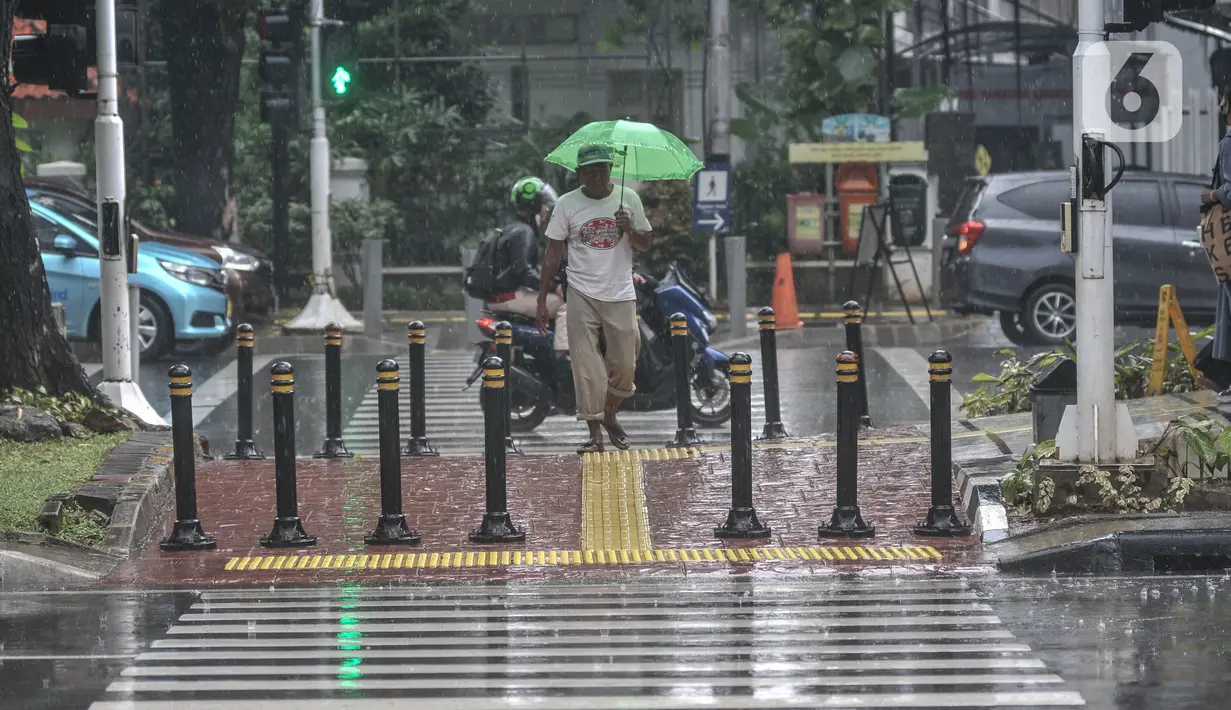 Warga menggunakan payung saat hujan mengguyur kawasan Monas, Jakarta Pusat, Kamis (5/1/2023). Badan Meteorologi, Klimatologi, dan Geofisika (BMKG) menyatakan beberapa wilayah Indonesia seperti Sumatera bagian selatan, Jawa, dan Bali mulai memasuki periode puncak musim hujan. (merdeka.com/Iqbal S Nugroho)