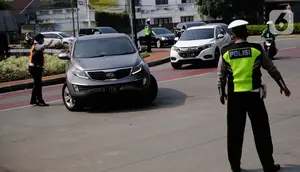 Petugas polisi mengarahkan kendaraan berplat nomor genap di pos penyekatan ganjil-genap di Bundaran Senayan, Minggu (5/9/2021). Pembatasan kendaraan dengan sistem pelat nomor kendaraan ini tetap berlaku di akhir pekan, Sabtu dan Minggu. (Liputan6.com/Angga Yuniar)