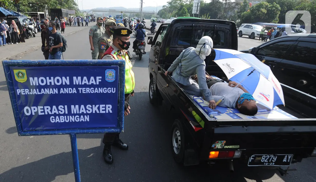 Petugas memperhatikan warga sakit yang dievakuasi dengan mobil saat Operasi Masker Gabungan di Perempatan Ciawi, Bogor, Kamis (10/9/2020). Razia masker yang dilakukan Pemkot dan Pemkab Bogor ini menyasar warga yang tidak mengenakan masker dengan denda sebesar Rp 100.000. (merdeka.com/Arie Basuki)