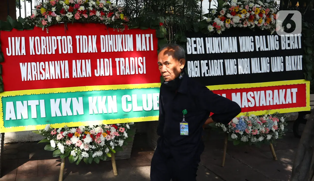 Petugas keamanan melintasi karangan bunga yang terpajang di depan PN Jakarta Pusat, Senin (12/10/2020). Karangan bunga yang mengharapkan keadilan tersebut berjejer menjelang sidang vonis terdakwa kasus dugaan korupsi di PT Asuransi Jiwasraya (Persero). (Liputan6.com/Angga Yuniar)