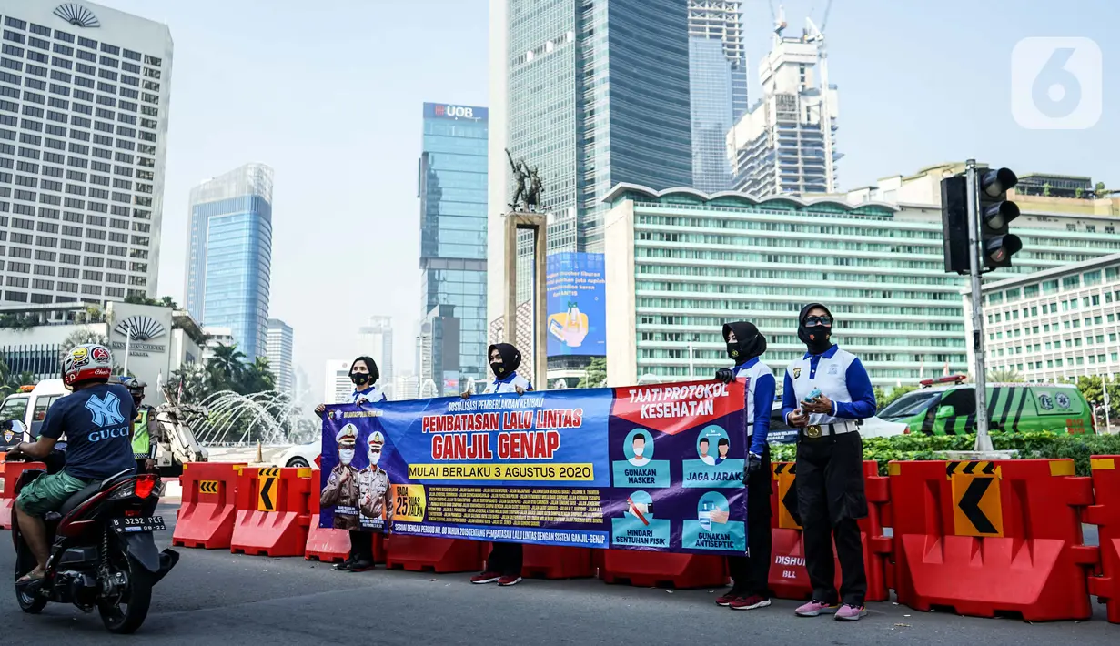 Petugas kepolisian membentangkan spanduk saat sosialisasi pelaksanaan ganjil genap di Kawasan Bundaran HI, Jakarta, Minggu (2/8/2020). Ditlantas Polda Metro Jaya kembali memberlakukan sistem ganjil genap di 25 ruas jalan protokol  DKI Jakarta mulai Senin, 3 Agustus 2020. (Liputan6.com/Faizal Fanani)