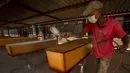 Seorang pekerja mengecat peti mati saat proses pembuatan di bengkelnya, Evaton, selatan Johannesburg, Afrika Selatan, Senin (15/2/2021). Maseko mengatakan, bahan dan biaya pembuatan peti mati telah naik karena pemasok yang lebih sedikit dampak pandemi COVID-19. (AP Photo/Themba Hadebe)