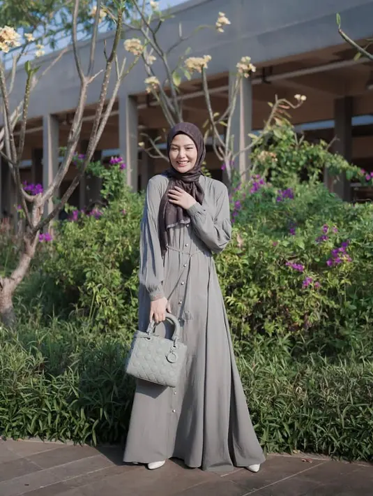 <p>Tampil anggun, Dara Arafah tampak memadukan gamis berwarna abu-abu dengan aksen kancing di bagian depan dengan scarf monogram berwarna coklat. Ia melengkapi penampilannya dengan tas Dior warna senada dengan gamisnya, serta heels berwarna putih. (Instagram/daraarafah).</p>