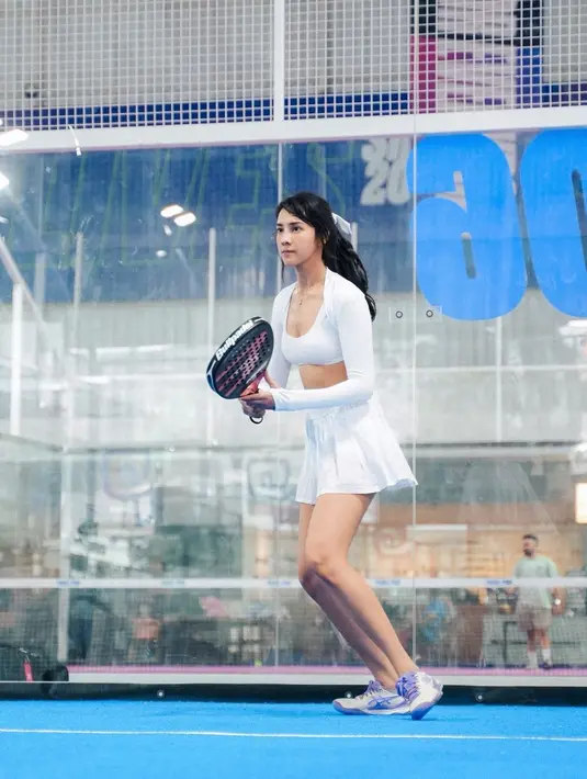 Ia mengenakan sport bra dengan cropped outer dan mini skirt tenis berwarna putih. Outfit sporty ini ditutup dengan sneakers putih ungu [@anyageraldine]
