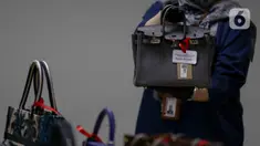 Petugas Komisi Pemberantasan Korupsi (KPK) menunjukkan salah satu tas mewah yang akan dilelang pada kegiatan Aanwijzing lelang barang rampasan hasil kasus korupsi yang ditangani di Rumah Penyimpanan Benda Sitaan Negara (Rupbasan), Jakarta, Kamis, (5/12/2024). (Liputan6.com/Herman Zakharia)