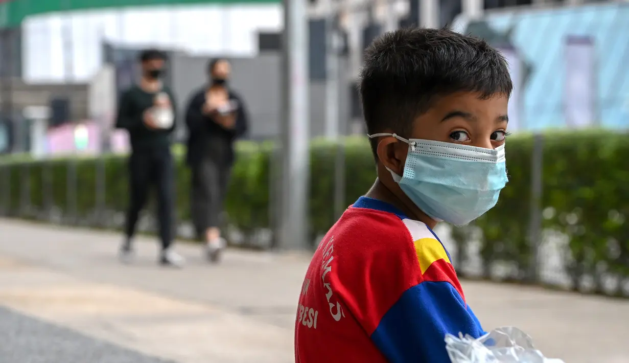 Seorang anak laki-laki yang mengenakan masker duduk di pinggir jalan di Kuala Lumpur, Malaysia (24/11/2020). Malaysia pada Selasa (24/11) melaporkan 2.188 kasus baru COVID-19 dalam lonjakan harian tertinggi sejak wabah coronavirus merebak di negara itu. (Xinhua/Chong Voon Chung)