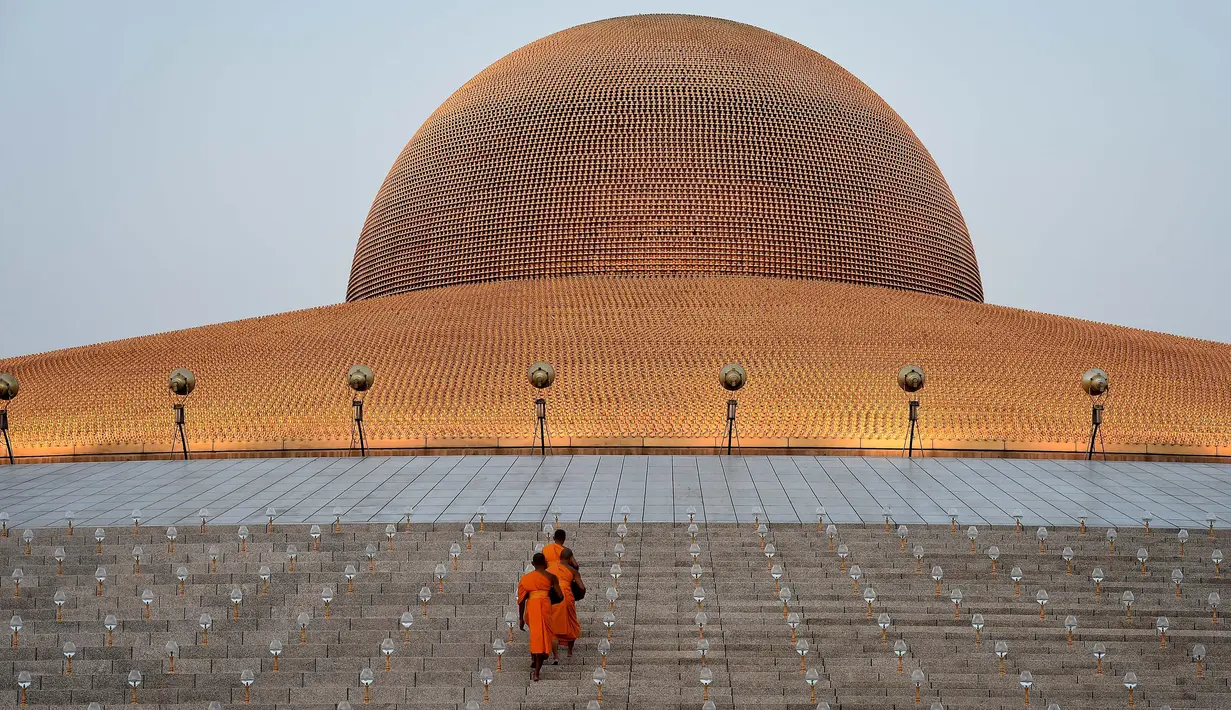 Sejumlah biksu turun dari kubah untuk menerima sedekah usai ritual Makha Bucha Day di kuil Wat Dhammakaya, Bangkok, Thailand (11/2). Makha Bucha Day bertujuan merayakan ajaran pertama Sang Buddha kepada para pengikutnya. (AFP/Lillian Suwanrumpha)
