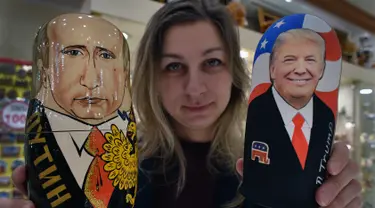 Seorang penjaga toko menunjukan Matryoshka yang berkarakter Presiden Rusia, Vladimir Putin dan Presiden Amerika Serikat terpilih Donald Trump di Moskow, Rusia (16/1). (AFP/Alexander Nemenov)