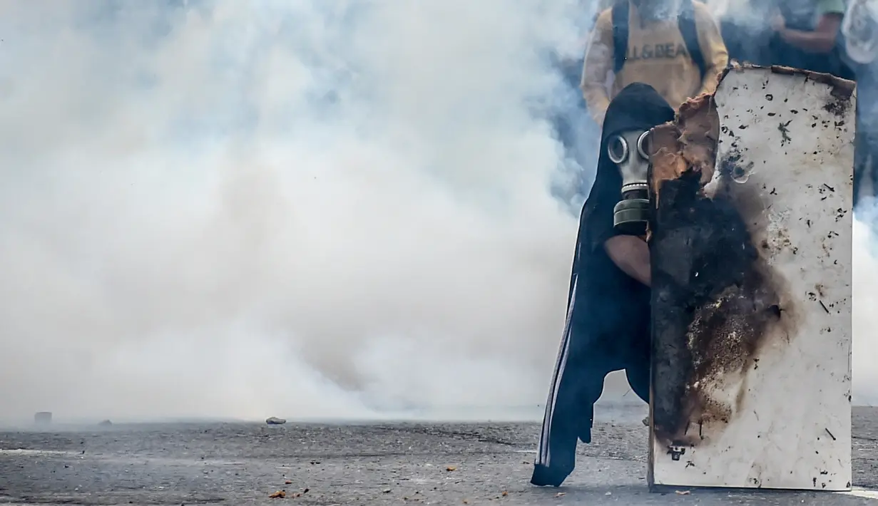 Asap gas air mata menyelimuti seorang demonstran saat aksi  menentang Presiden Venezuela Nicolas Maduro, di Caracas, kamis (20/4). Tiga orang dikabarkan tewas dalam aksi demonstrasi tersebut.  (AFP PHOTO / Juan BARRETO)
