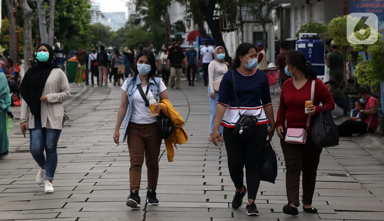 Pengunjung menggunakan masker berjalan-jalan di kawasan Kota Tua Jakarta, Kamis (29/10/2020). Libur panjang di masa pemberlakuan PSBB transisi Jakarta dimanfaatkan warga untuk mengunjungi lokasi-lokasi wiisata. (Liputan6.com/Helmi Fithriansyah)