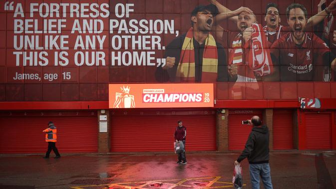 Seorang penggemar Liverpool berfoto di bawah layar digital baru merayakan Liverpool menyegel gelar Liga Premier malam sebelumnya, di luar stadion Anfield di Liverpool, Inggris (26/6/2020). (AFP Photo/Oli Scarff)